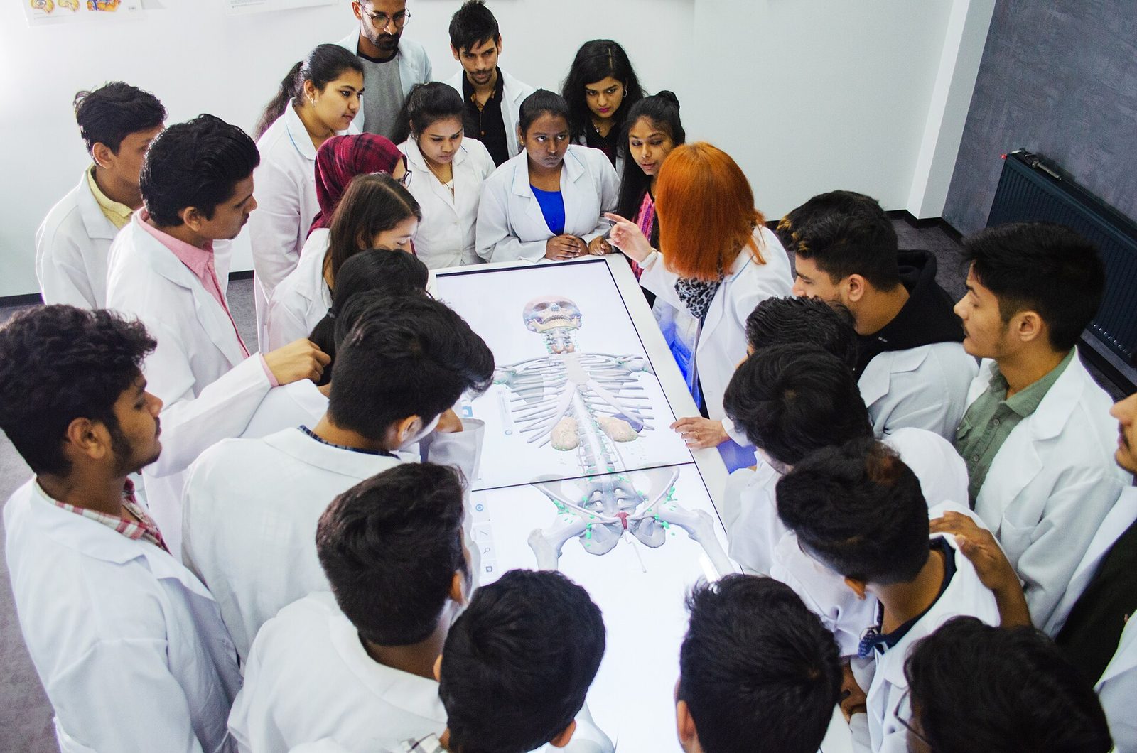 Students gathered around an Anatomage virtual dissection table during an anatomy class.